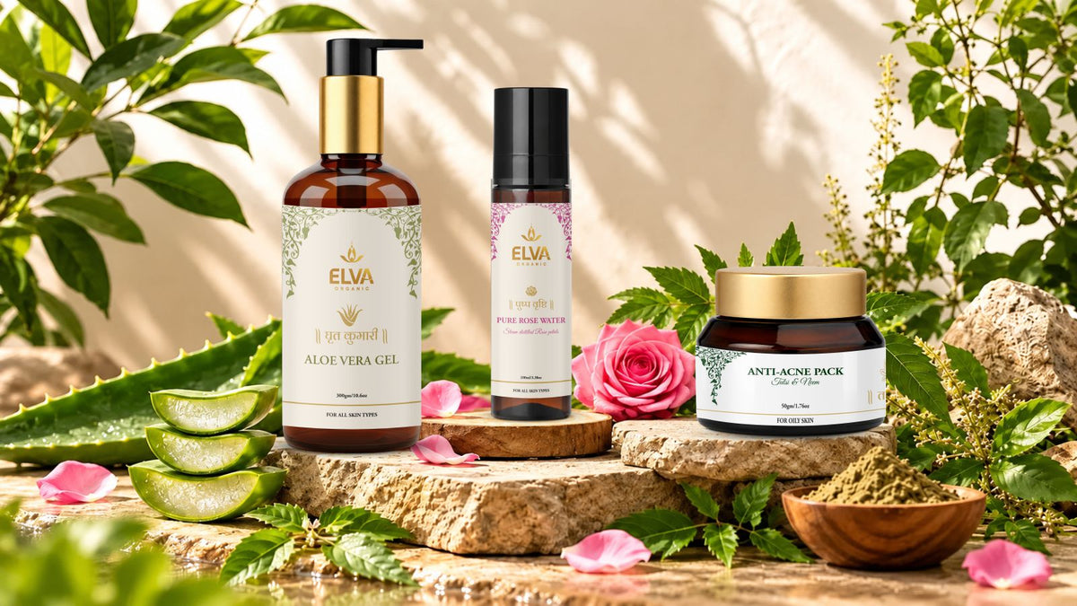 Three ELVA skincare products arranged on stone blocks with aloe vera slices, rose petals, and greenery: an amber bottle of Aloe Vera Gel, a small black pump bottle, and a dark jar labeled Antioxidant Pack, styled in a natural setting.